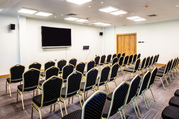 Conference hall with empty chairs and projection screen for video presentations