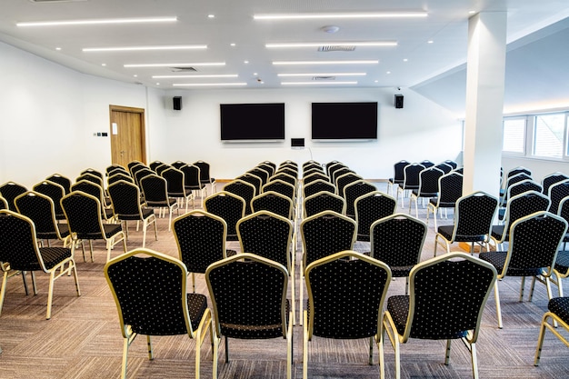 Conference hall with empty chairs and projection screens for video presentations