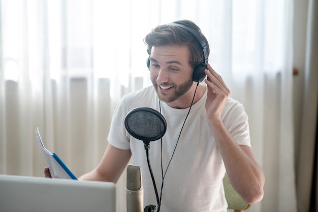 Conference. Young bearded man sitting in headphones and speaking in microphone