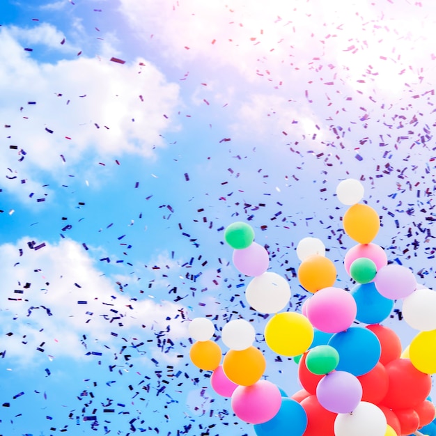 Confetti and balloons on a background of blue sky with clouds. Holiday concept, festive atmosphere.