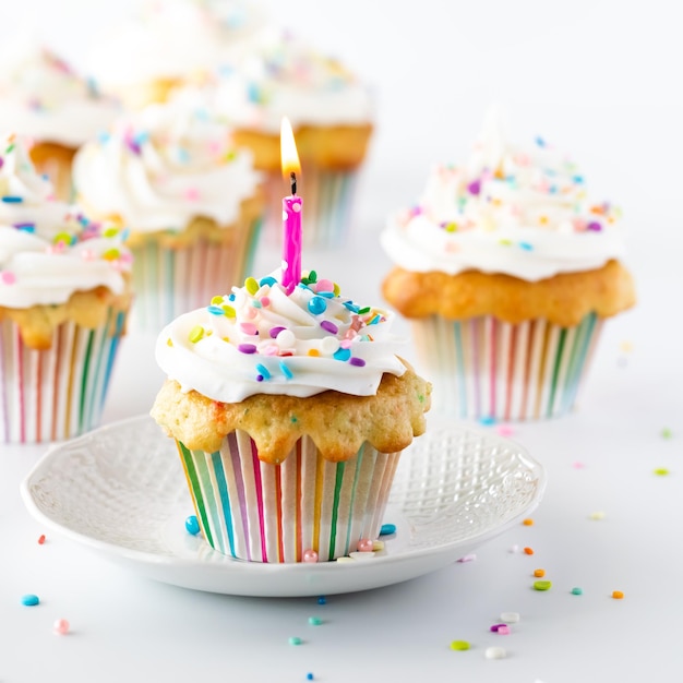 Foto un cupcake di confetti con una candela accesa con altri cupcake in messa a fuoco morbida dietro