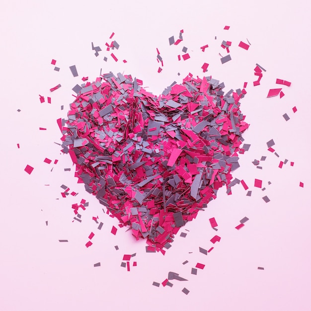 Confetti in heart shape decoration on pink, top view