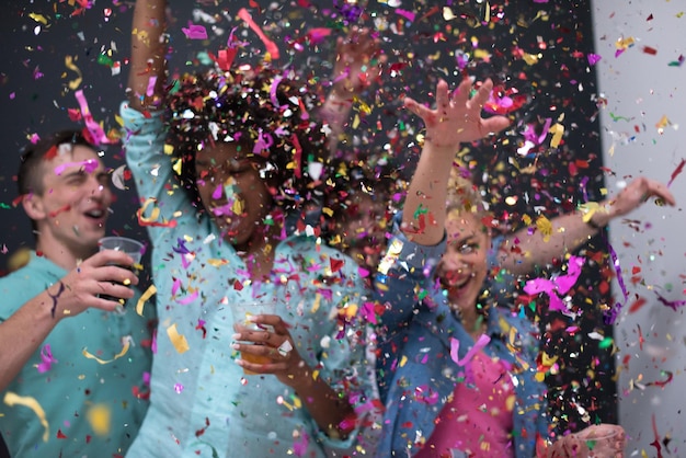 confetti party Multiethnics groep gelukkige jonge mensen die oudejaarsavond vieren terwijl ze dansen en thuis plezier hebben
