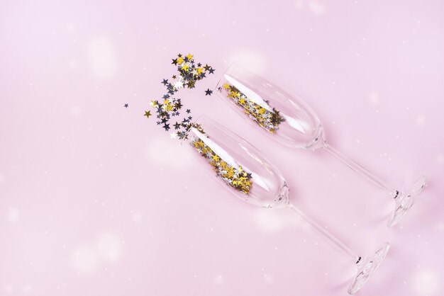 Confetti in the Shape of Stars Poured out Glasses of Champagne on the Pink Background Top View