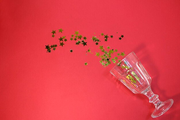 Confetti in the shape of stars poured out glasses. Christmas and new year background. Top view.