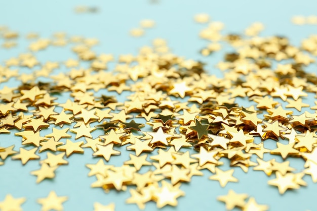 Confetti stars on light blue background closeup Christmas celebration