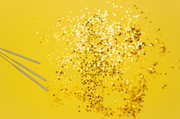 Confetti stars and sparkler sticks on yellow