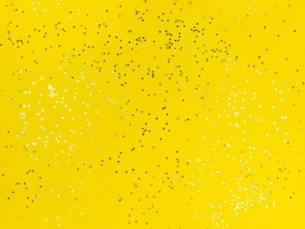 Confetti-sterren die op een gele achtergrond schitteren.