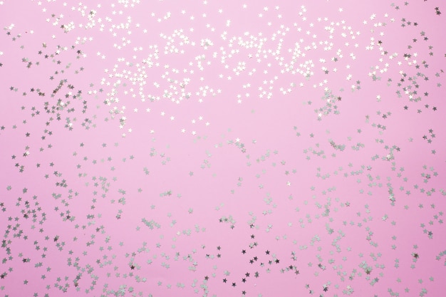 Confetti van gouden sterren glinsteren op een roze achtergrond. Feestelijke vakantie pastel achtergrond.