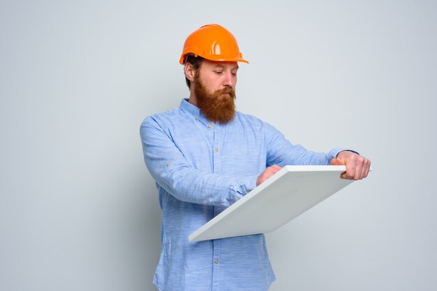 Confidant architect with beard and orange helmet does a sketch