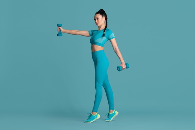 Confidence. Beautiful young female athlete practicing in studio, monochrome blue portrait