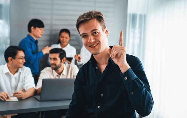 Confidence and happy smiling businessman portrait with background of his colleague and business team working in office Office worker teamwork and positive workplace concept Prudent