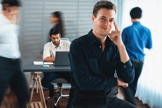 Confidence and happy smiling businessman portrait with blur motion background of his colleague and business team working in office Office worker teamwork and positive workplace concept Prudent