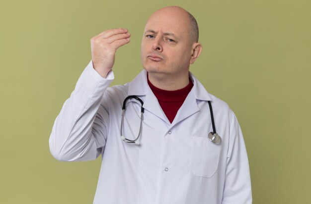 Confident adult slavic man in doctor uniform with stethoscope pretending to hold something 