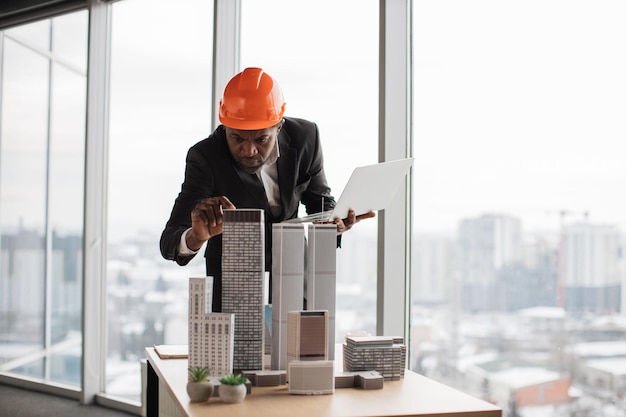Photo confident african american man in suit using laptop looking at the architecture design of buildings