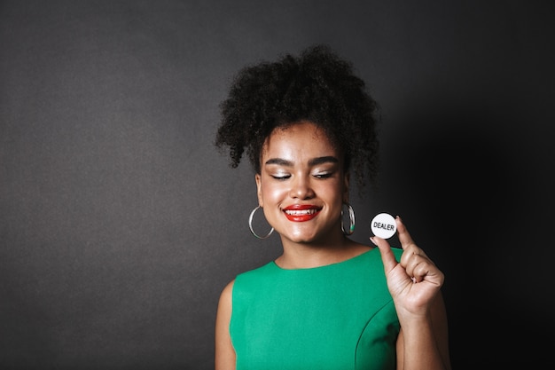 Confident african woman wearing dress standing isolated over black space