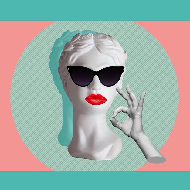 Confident antique female statue's head in black sunglasses with red lips shows the ok gesture