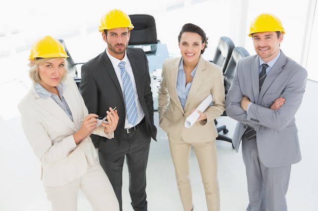 confident architects with hard hats and blueprint in office