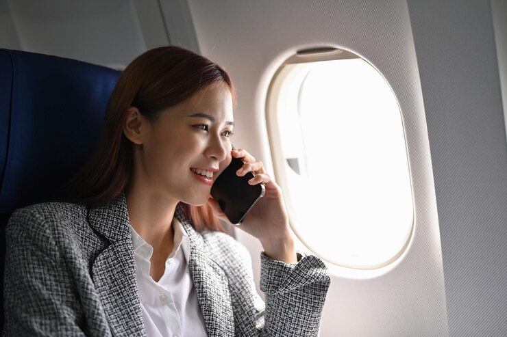 Photo 飛行機で別の都市に出張しながら電話で自信を持ってアジアの実業家