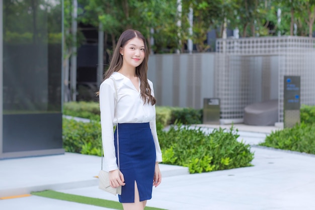 Confident Asian businesswoman wearing white shirt smiling looking at camera happily while walking