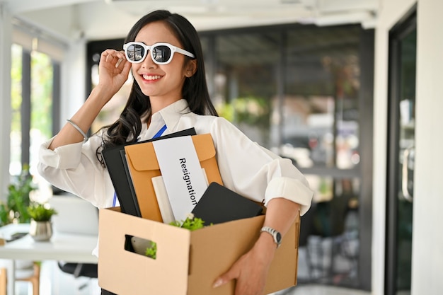 Уверенная азиатская офисная работница в солнечных очках счастлива бросить работу