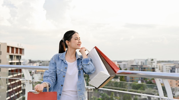 市内のショッピングセンターで買い物をする買い物袋を運ぶ自信のあるアジア人女性