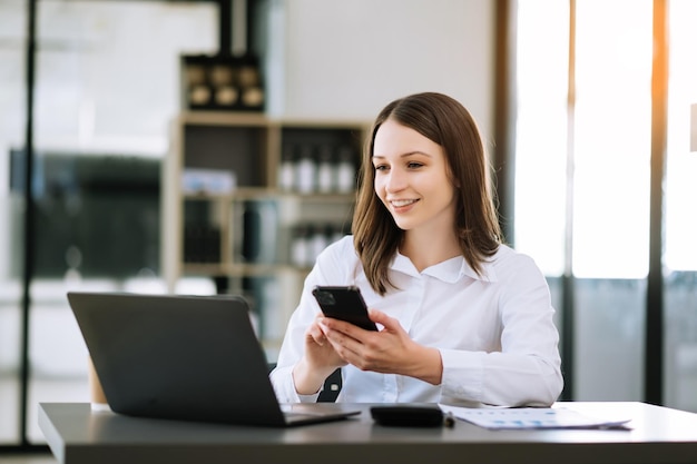 Confident Asian woman with a smile standing holding notepad and tablet at the modern officexAxA