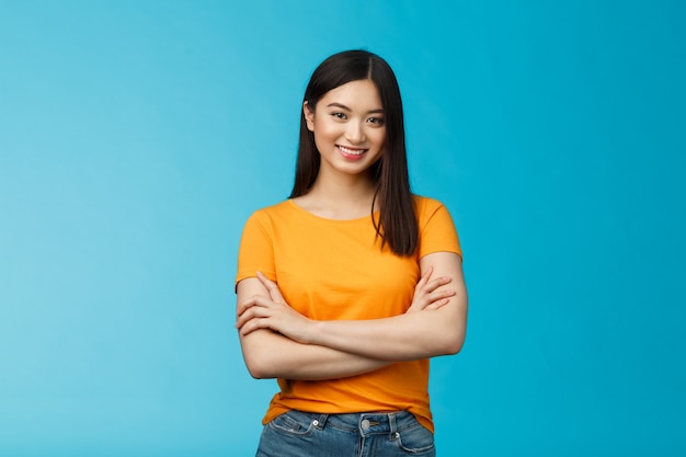 Confident assertive good-looking asian girl with dark short hairstyle cross arms chest self-assured, ready help give advice friendly smiling camera, stand blue background upbeat motivated