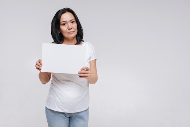 Confident attractive lady posing  while standing and holding up a sign