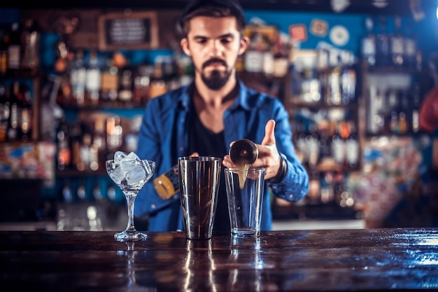 Confident barman decorates colorful concoction in the night club