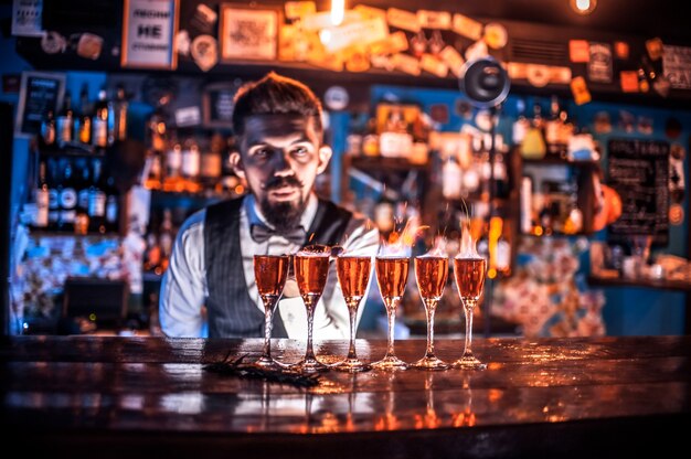 Confident bartender demonstrates his professional skills while standing near the bar counter in bar