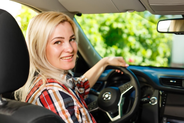 自信を持って美しい。車を運転するカジュアルな服装で魅力的な若い女性