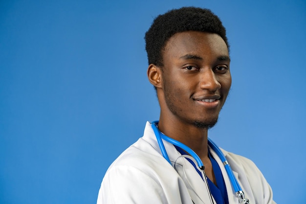 Confident black doctor posing over blue studio background