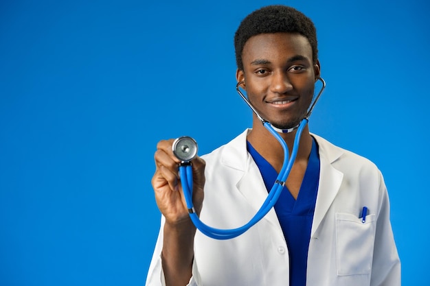 Уверенный черный врач позирует на синем фоне студии