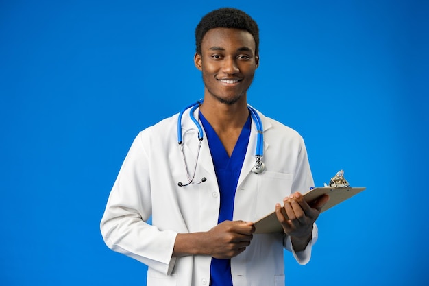 confident black doctor posing over blue studio background