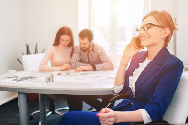 Broker fiducioso con venditori domestici dietro. coppia giovane famiglia acquisto affitto proprietà immobiliare. agente che dà consulenza a uomo e donna. firma contratto per acquisto casa o appartamento o appartamenti.