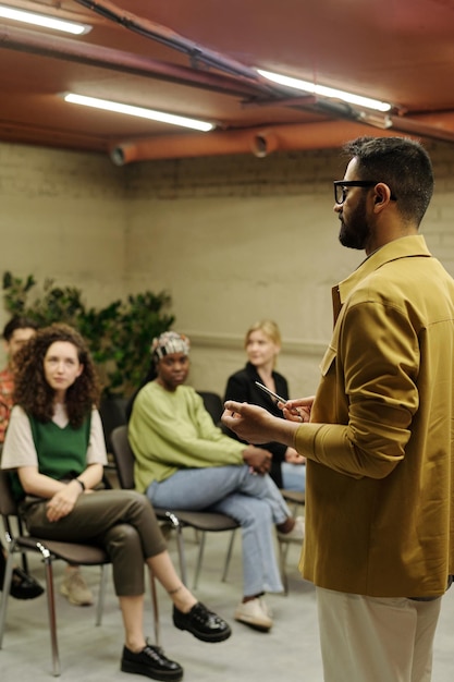 Foto fiducioso business coach in piedi davanti al pubblico durante la presentazione