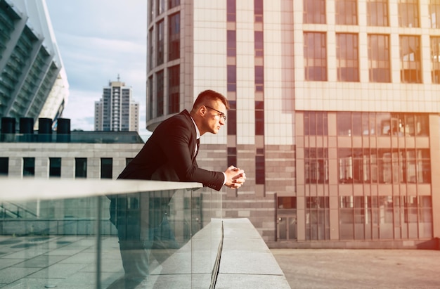 Confident business man in formal wear and glasses while standing outdoors looking away with cityscape in the background