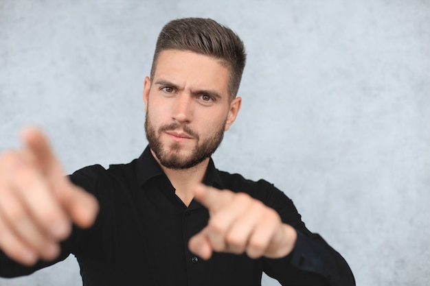 Confident business man is pointing finger at you isolated over gray background.