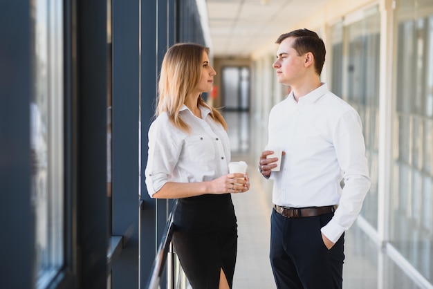 Confident business partners walking down in office building and discussing work