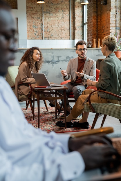 Confident business people interacting by table with African colleague in front