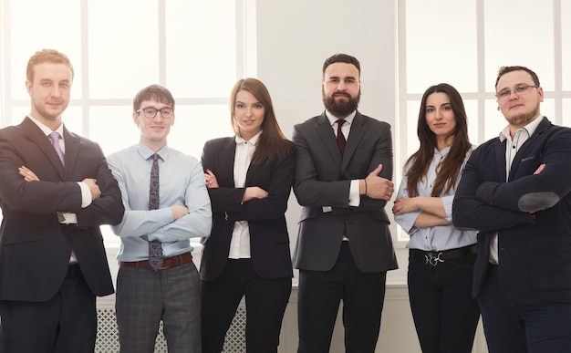 Confident business people in office. Successful professional team posing for photo, standing at window, motivation and success concept, copy space
