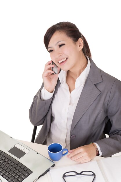 Confident business woman using cellphone and sitting on chair at office on white background.