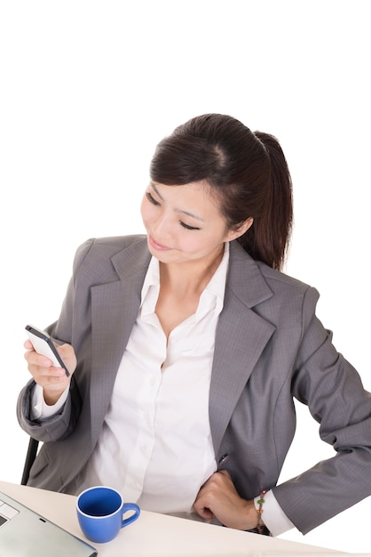 Confident business woman using cellphone and sitting on chair at office on white background.