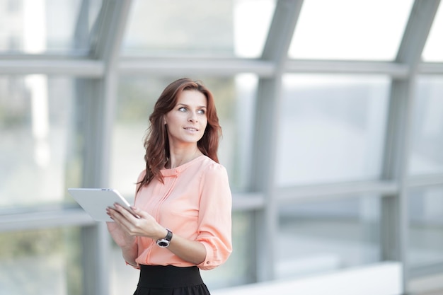 Confident business woman with digital tablet on blurred office background