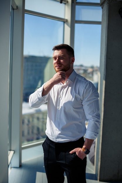 Confident businessman, boss man standing in modern office, successful leader, business owner thinking about future success, planning new opportunities