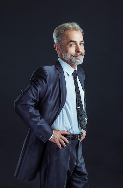 Confident businessman in a business suit on a black background.