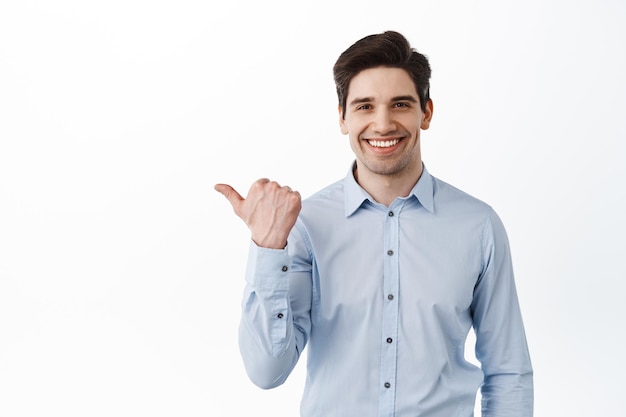 Confident businessman, ceo manager pointing left at promo text and smiling, recommending company banner, showing advertisement, white background