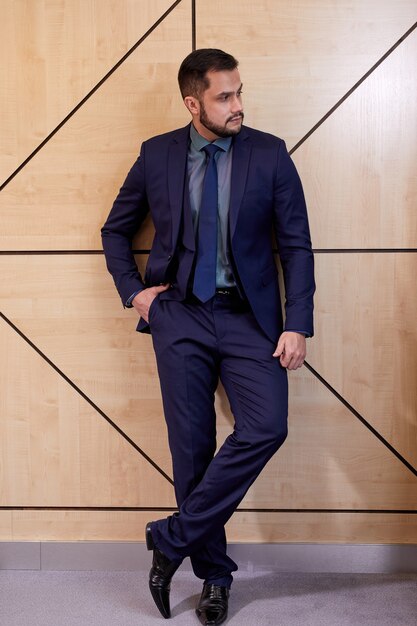 Confident businessman in elegant blue suit posing isolated in boardroom, stand looking at side. business people concept