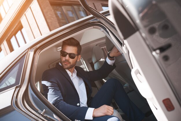 Photo confident businessman fashionable man coming out of a car